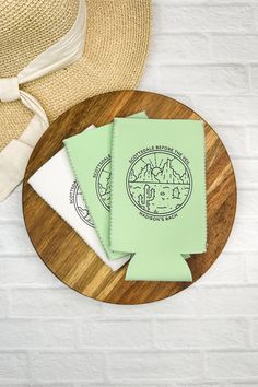 two green napkins sitting on top of a wooden plate next to a straw hat