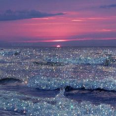 the sun is setting over the ocean and stars are shining on the water in this photo