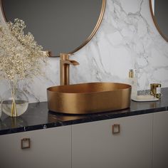 a bathroom with marble counter tops and gold fixtures on the vanity, along with a round mirror