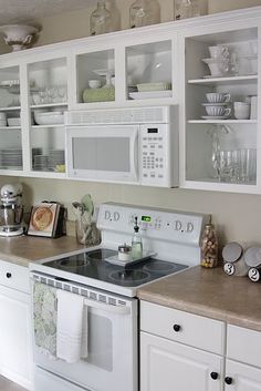 a kitchen with white cabinets and counter tops