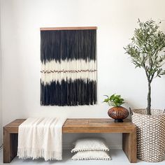 a wooden bench sitting next to a potted plant on top of a hard wood floor