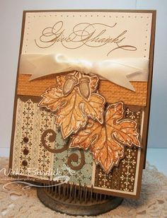 a close up of a card on a doily with a ribbon and some leaves