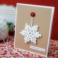 a white snowflake is hanging from a string on top of a red tablecloth