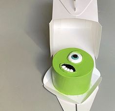 a green cake in a white box with eyes on it