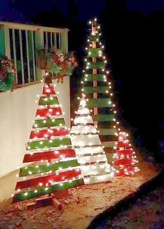 three christmas trees are lit up outside at night