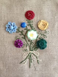 a bunch of different colored flowers on a piece of cloth with some thread in the middle