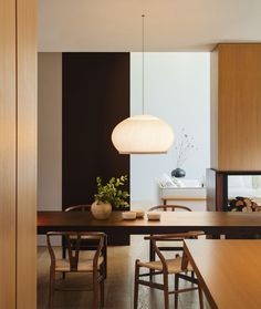 a dining room table with chairs and a lamp hanging from it's center point