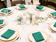 the table is set with green napkins and place settings