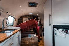 a woman is standing in the kitchen area of an rv