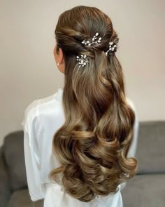 the back of a woman's head with long wavy hair and flowers in her hair