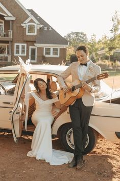 the bride and groom are getting out of their car to play the guitar for each other