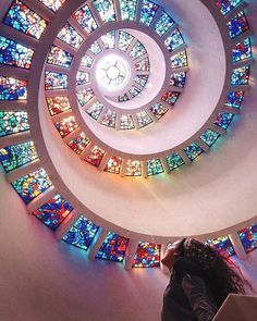 a woman standing in front of a spiral stained glass window