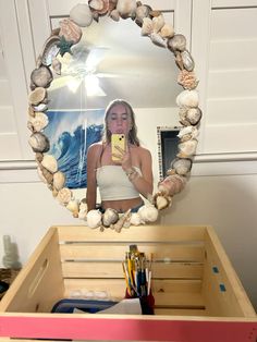 a woman taking a selfie in front of a mirror with seashells on it