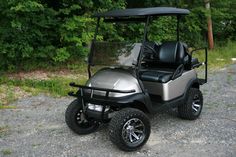 a silver and black golf cart parked on gravel