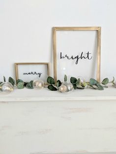 a white mantle with two framed photos and greenery