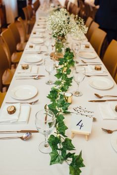 a long table is set with place settings and flowers