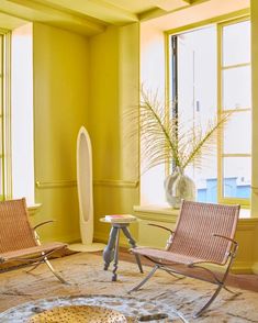 two chairs and a table in front of a window with yellow paint on the walls