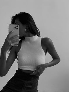 a woman taking a selfie with her cell phone while wearing a skirt and crop top