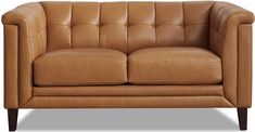 a tan leather couch sitting on top of a white floor