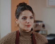 a woman wearing a brown sweater and red suspenders is looking at the camera with an intense look on her face