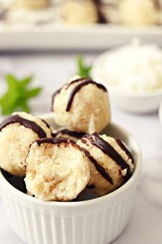 raw coconut macaroons in a bowl with chocolate drizzled on top