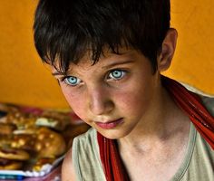 a young boy with blue eyes stares at the camera