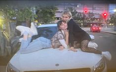 two women sitting on the hood of a car