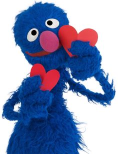 a blue stuffed animal holding two red hearts