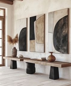 three vases are sitting on a wooden bench in front of two wall hangings