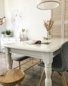 a white dining table with grey chairs and a wooden bench in front of the table