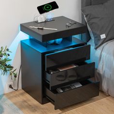 a black night stand with three drawers and a cell phone on the top one drawer