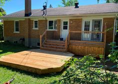 a wooden deck in front of a brick house