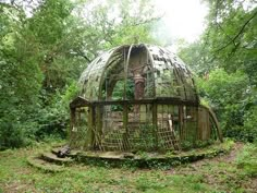 a round wooden structure sitting in the middle of a forest