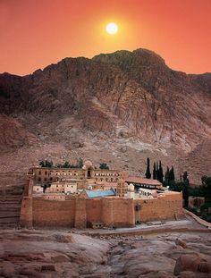 the sun is setting over an adobe - style building on top of a rocky mountain