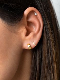 a woman wearing an ear cuff with two small gold bars on the side of her ear