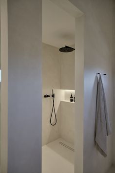 a white bathroom with a shower head and towel hanging on the wall next to it