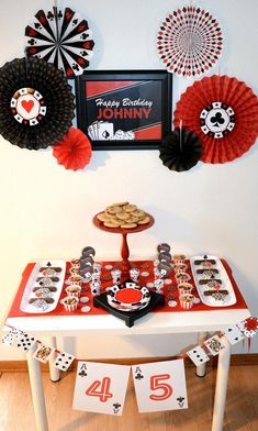 a red table topped with lots of cupcakes and cookies next to paper fans