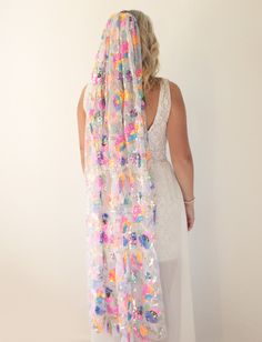 a woman wearing a white dress and a veil with colorful sequins on it