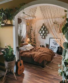 a bed room with a guitar on the floor and plants hanging from the wall behind it