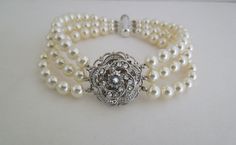 "This vintage inspired bracelet has a Victorian style rose with Swarovski crystals and three strands of Swarovski pearls in ivory/cream. Pendant measures just under 1\" in diameter, pearls measure 6 mm. Bracelet measures approximately 7 1/4\" long. Swarovski pearls are available in different colors, and can be made in different finishes and lengths. Please choose yours at checkout. This is the perfect addition for your vintage inspired wedding or special occasion event. What a romantic piece for Cream Wedding Bracelet Jewelry, Vintage Pearl Bracelet For Wedding, Elegant Pearl Bracelet For Mother Of The Bride, Elegant Cream Pearl Beaded Bracelets, Elegant Cream Beaded Pearl Bracelet, Elegant Cream Pearl Bracelet, Elegant Cream Pearl Bracelet For Wedding, Elegant Beaded Cream Bracelets, Elegant Cream Pearl Bracelets