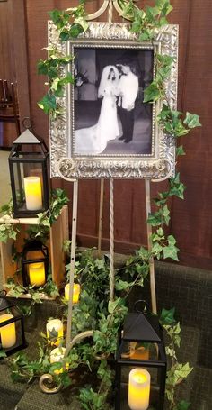 a wedding photo frame with candles and greenery