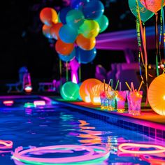 there are many balloons and drinks on the edge of the pool at this party,