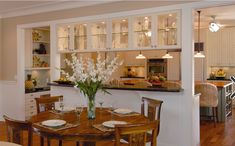 a dining room table with place settings and flowers in the vase on the centerpiece