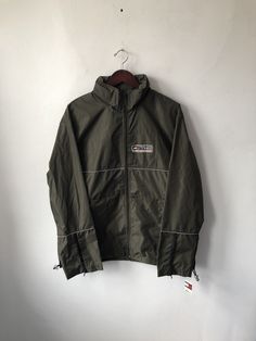 "2000 tommy hilfiger lightweight jacket. deadstock. NWT. olive green water resistant shell. 3M trim. clear zip-out hood. full front zip closure. velcro side pockets. adjustable waist cord. front graphic. sewn brand fabric patches on back & bottom. 30\" long. 25\" across. 26.5\" from shoulder to hem. in excellent, unworn condition. fresh american style. legit. legitvintage.etsy.com legitvintage on instagram" Spring Military Style Windbreaker For Outdoor Activities, Military Style Windbreaker For Spring Outdoor Activities, Spring Military Windbreaker For Outdoor Activities, Green Windbreaker With Zipper For Streetwear, Green Zipper Windbreaker For Streetwear, Khaki Nylon Track Jacket For Winter, Khaki Windbreaker With Zipper For Streetwear, Khaki Windbreaker With Zipper Closure For Outdoor, Green Utility Windbreaker For Streetwear