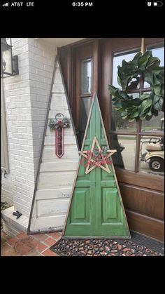 a christmas tree made out of an old door and some other decorations on the front porch