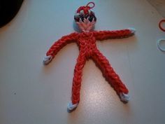 a red and white knitted doll laying on top of a table next to scissors