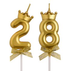 two gold birthday candles with the number twenty eight on them and a crown on top