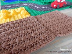 a crocheted blanket is laying on the floor next to a toy truck and car