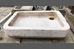 an old white sink sitting on top of a cement slab