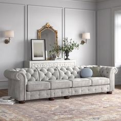 a living room with a couch, mirror and rug on the floor in front of it